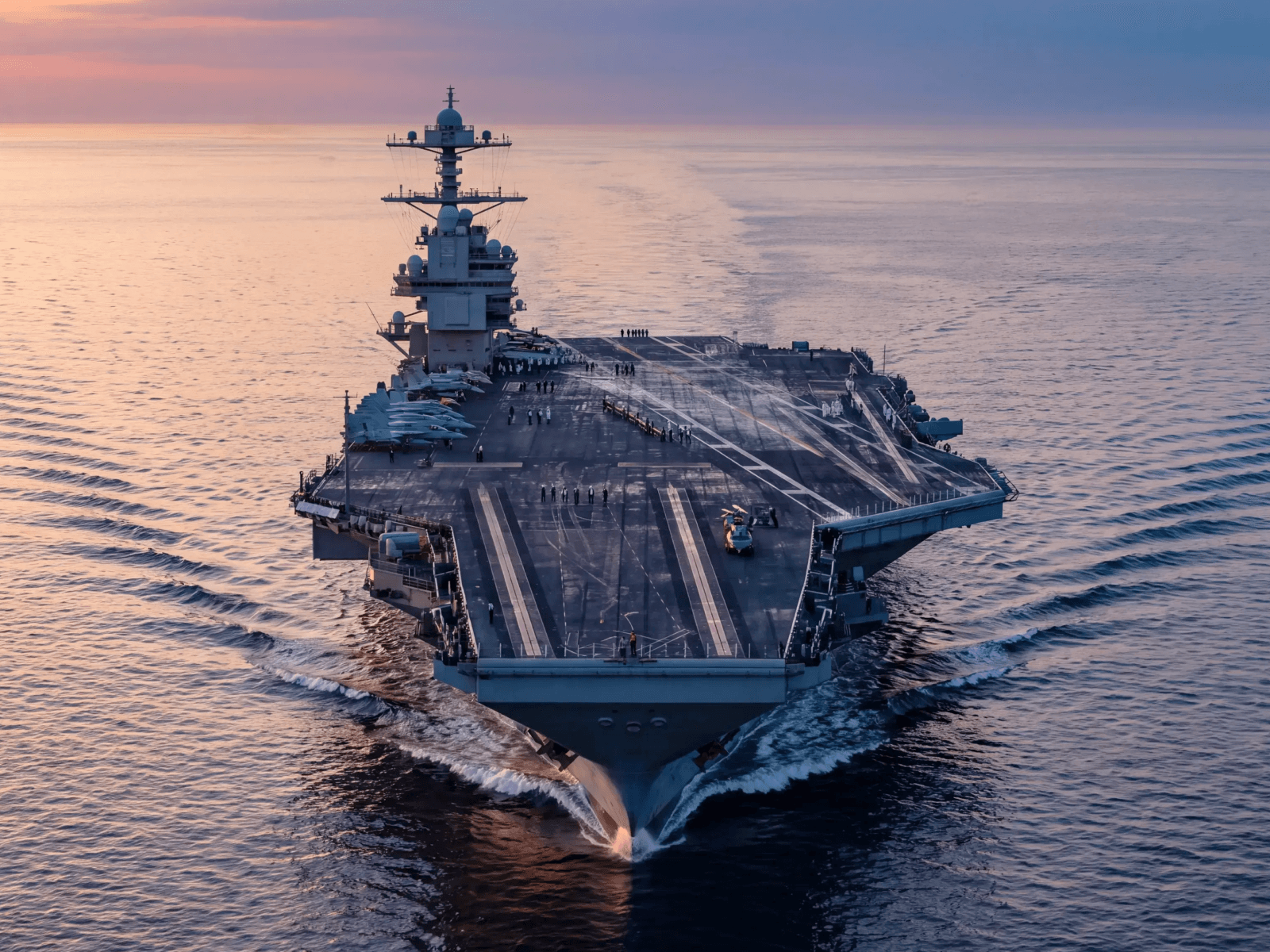 Aircraft carrier underway at sea at sunset